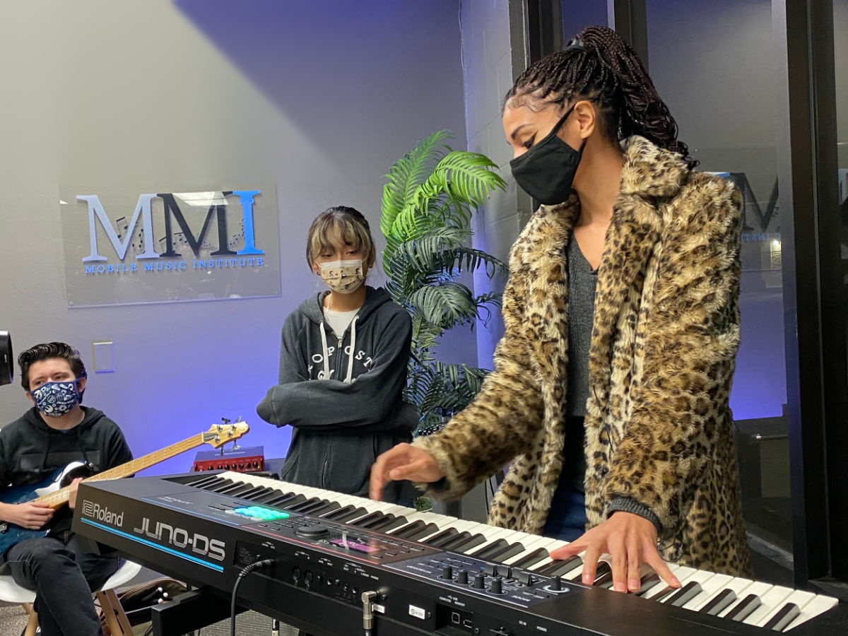 An instructor plays a keyboard while students watch at the Mobile Music Institute music nonprofit.
